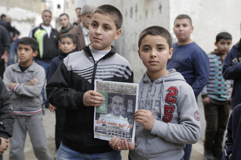 Family members of Ibrahim Akkari hold his picture as a martyr at their home in the Shuafat refugee camp, after he was shot dead by Israeli police, following his driving attack in Jerusalem. The Shuafat man drove his car into a crowd of people waiting by the Shimon ha Tzadik lightrail station in Jerusalem injuring at least 8 people, and killing at least one bystander. The driver was shot and killed near the site of the attack. November 05, 2014. Photo by Sliman Khader/FLASH90