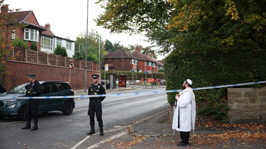 A member of the Jewish community holds a Torah behind a police cordon in Manchester, UK, on ​​October 2, 2025. Two people were killed in a car and knife attack on a synagogue, and the perpetrator was shot dead by police. Photo: EPA/Adam Vaughan