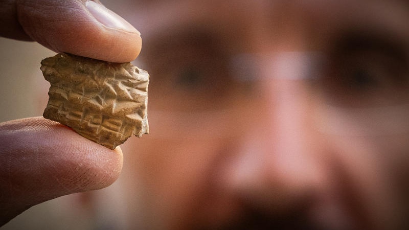 An Israeli Antiquities Authority (IAA) archaeologist holds a cuneiform inscription on a small pottery sherd, believed to reference a delay in payment from the Kingdom of Judah to the Assyrian Empire, discovered during an Israel Antiquities Authority archaeological excavation near the Western Wall in Jerusalem’s Old City, October 22, 2025. Photo by Yonatan Sindel/Flash90