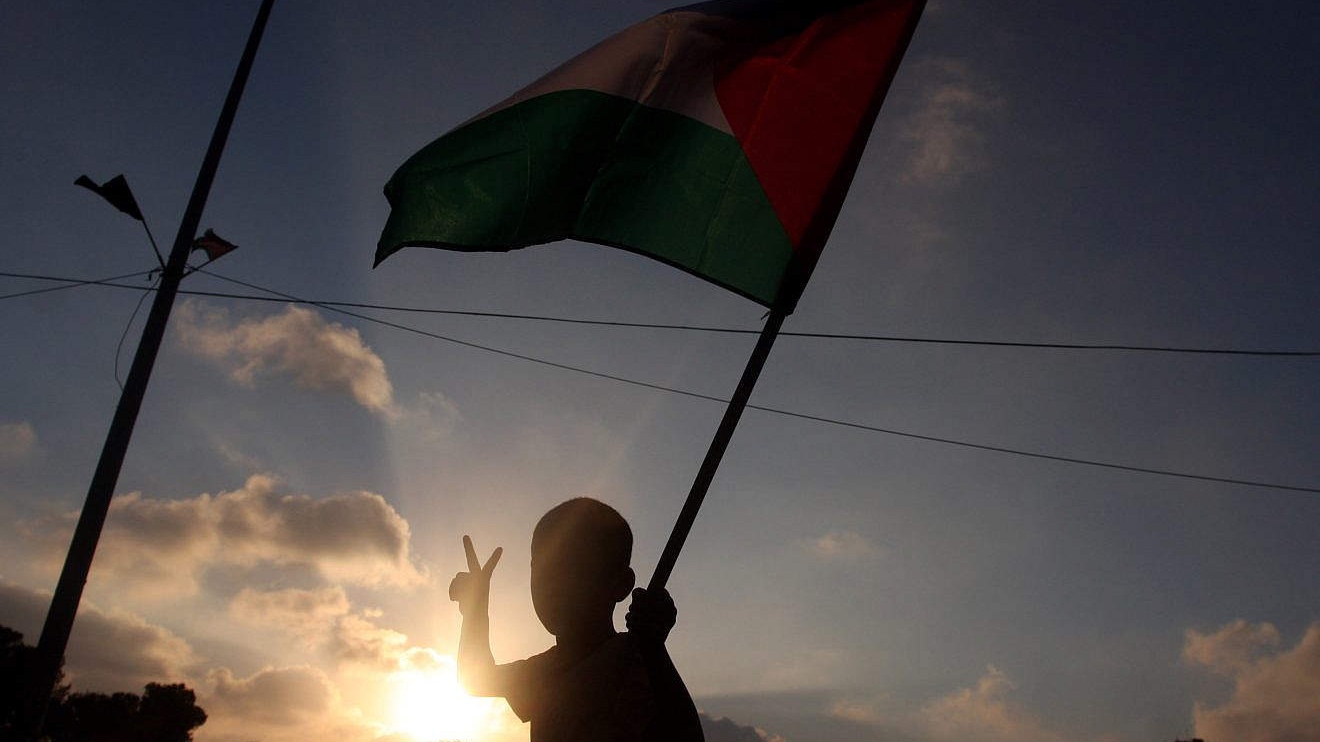 A child in the city of Ramallah holds a Palestinian national flag, while at the same time signing for peace, during a local protest against the Paris Protocol and the Oslo Accords, key agreements that govern economic ties between Israelis and Palestinians, Sept. 11, 2012. Photo by Issam Rimawi/Flash90.