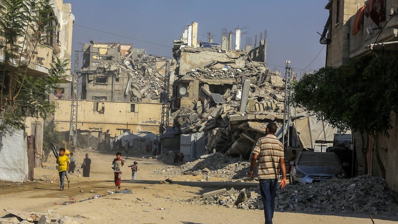 Palestinians walk past buildings destroyed in the recent war, in the Jorat al-Luth area, located between Rafah and Khan Yunis in the southern Gaza Strip, November 10, 2025. Photo by Abed Rahim Khatib/Flash90.