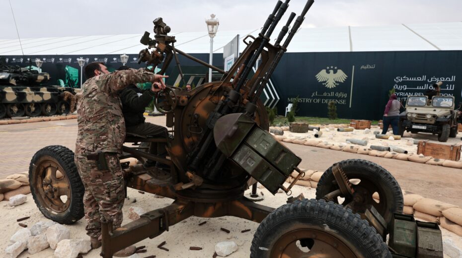 A soldier of the new Syrian army points to an anti-aircraft gun during a military display by the Ministry of Defense in Damascus on December 6, 2025, shortly before the first anniversary of the fall of the Assad regime. Photo: EPA/MOHAMMED AL RIFAI