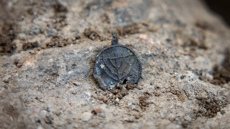 An Israeli Antiquities Authority (IAA) archaeologist holds a a 1,300-year-old menorah-decorated pendant discovered during an Israel Antiquities Authority archaeological excavation near the Western Wall in Jerusalem’s Old City, December 15, 2025. Photo by Yonatan Sindel/Flash90