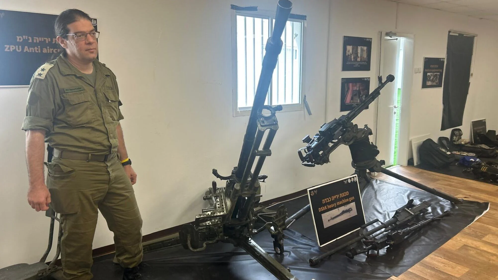 Lt. Col. (res.) Idan Sharon-Kettler, deputy commander of the Israel Defense Forces Asset Confiscation Unit, with captured Hamas heavy machine guns at Tzrifin Camp, December 2025. Photo by Amelie Botbol.