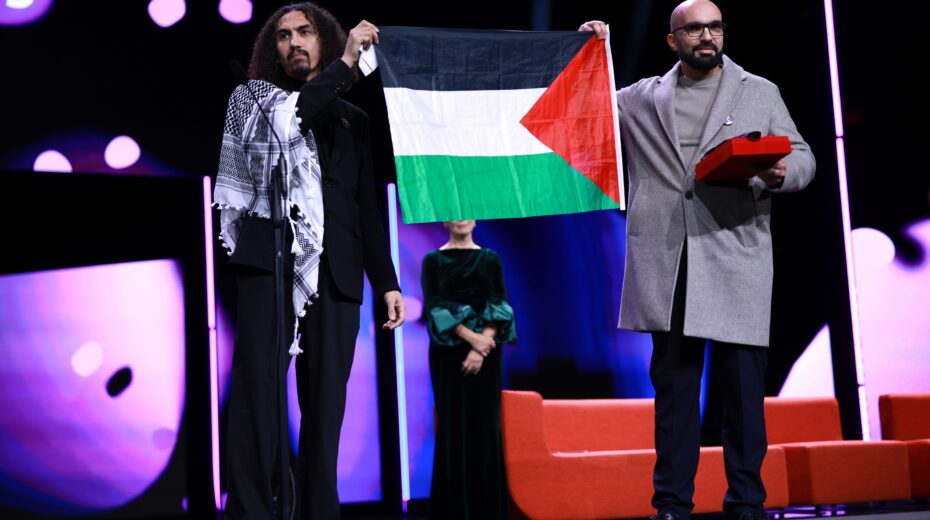 Abdallah Al-Khatib (left) and Taqiyeddine Issaad hold a Palestinian flag on stage at the closing gala of the 76th Berlin International Film Festival, after receiving the GWFF Award for Best Feature Film Debut for "Chronicles From the Siege." Berlin, February 21, 2026. Photo: EPA/Clemens Bilan