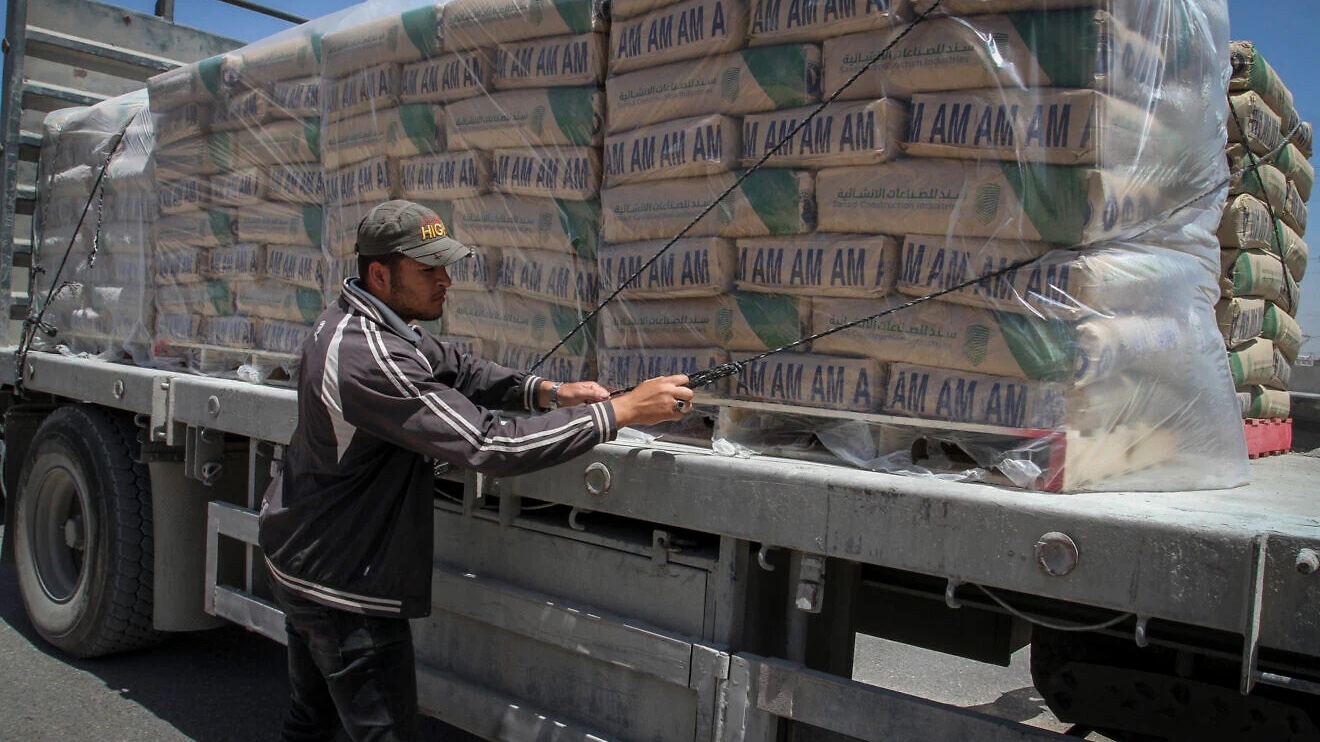 A Palestinian worker adjusts internationally funded bags of cement, which were loaded onto a truck after it entered the southern Gaza Strip from Israel through the Kerem Shalom border crossing in Rafah, April 29, 2015. Photo by Abed Rahim Khatib/Flash90.