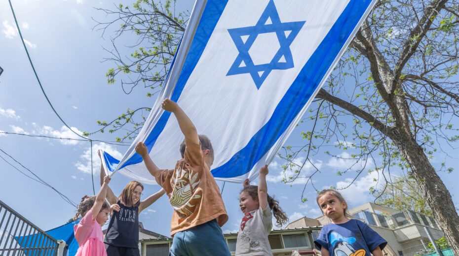 Israeli children play with a large Israeli flag at a kindergarten in Moshav Yashresh ahead of Independence Day. Photo: Yossi Aloni/Flash90