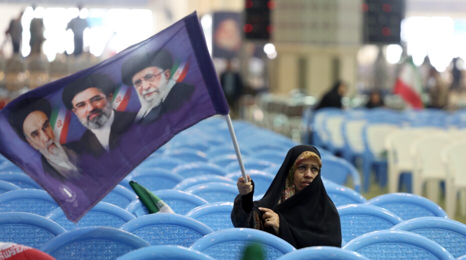 An Iranian woman holds a flag bearing the portraits of religious leaders Ayatollah Ruhollah Khomeini, Ayatollah Ali Khamenei, and the new Supreme Leader Mojtaba Khamenei at a memorial service for those killed in the Iran-US-Israel War at the Mosallah Mosque in Tehran (May 24, 2026). Photo: EPA/Abedin Taherkenareh