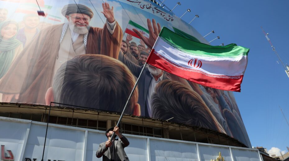 A man waves the Iranian national flag on Valiasr Square in Tehran in front of a giant portrait of the slain Supreme Leader Ayatollah Ali Khamenei. The photo was taken on April 10, 2026, shortly before the planned negotiations between Iran and the United States in Islamabad. Photo: Abedin Taherkenareh/EPA