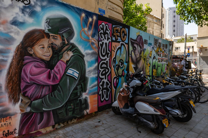 A mural in Tel Aviv shows a young girl embracing an Israeli soldier, surrounded by vibrant street art, on July 21, 2025. Photo by Chaim Goldberg/Flash90