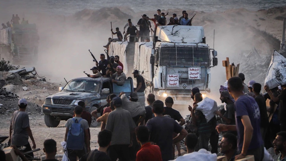 Armed Palestinians sit on trucks carrying humanitarian aid near the Zikim border crossing between Israel and Beit Lahia in the northern Gaza Strip, Aug. 18, 2025. Photo by Khalil Kahlout/Flash90.