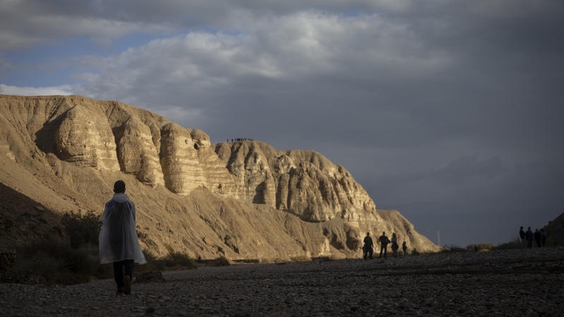 People watch as a waterfall flows through the desert cliffs near Qumran, in the Judean Desert, following heavy rainfall, December 29, 2025. Photo by Chaim Goldberg/Flash90