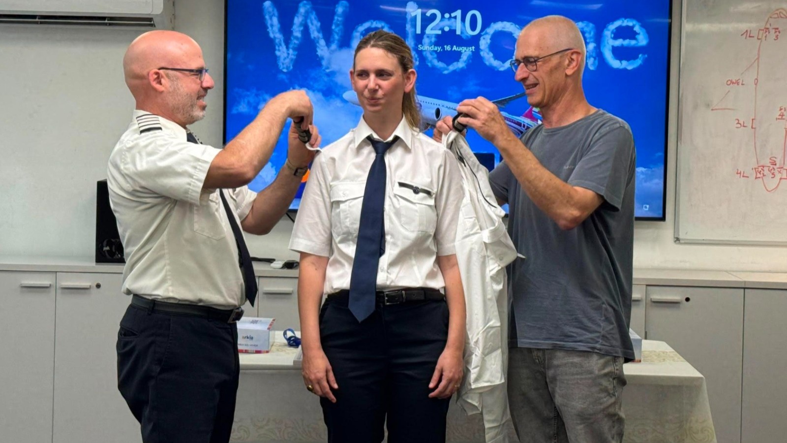 Adar Medotzki (C.) at the ceremonial appointment as captain at Arkia. On the right her father Tal Medotzki, also a captain at the airline, on the left Noam Adar, head of the Arkia fleet. Photo: Arkia Press Office