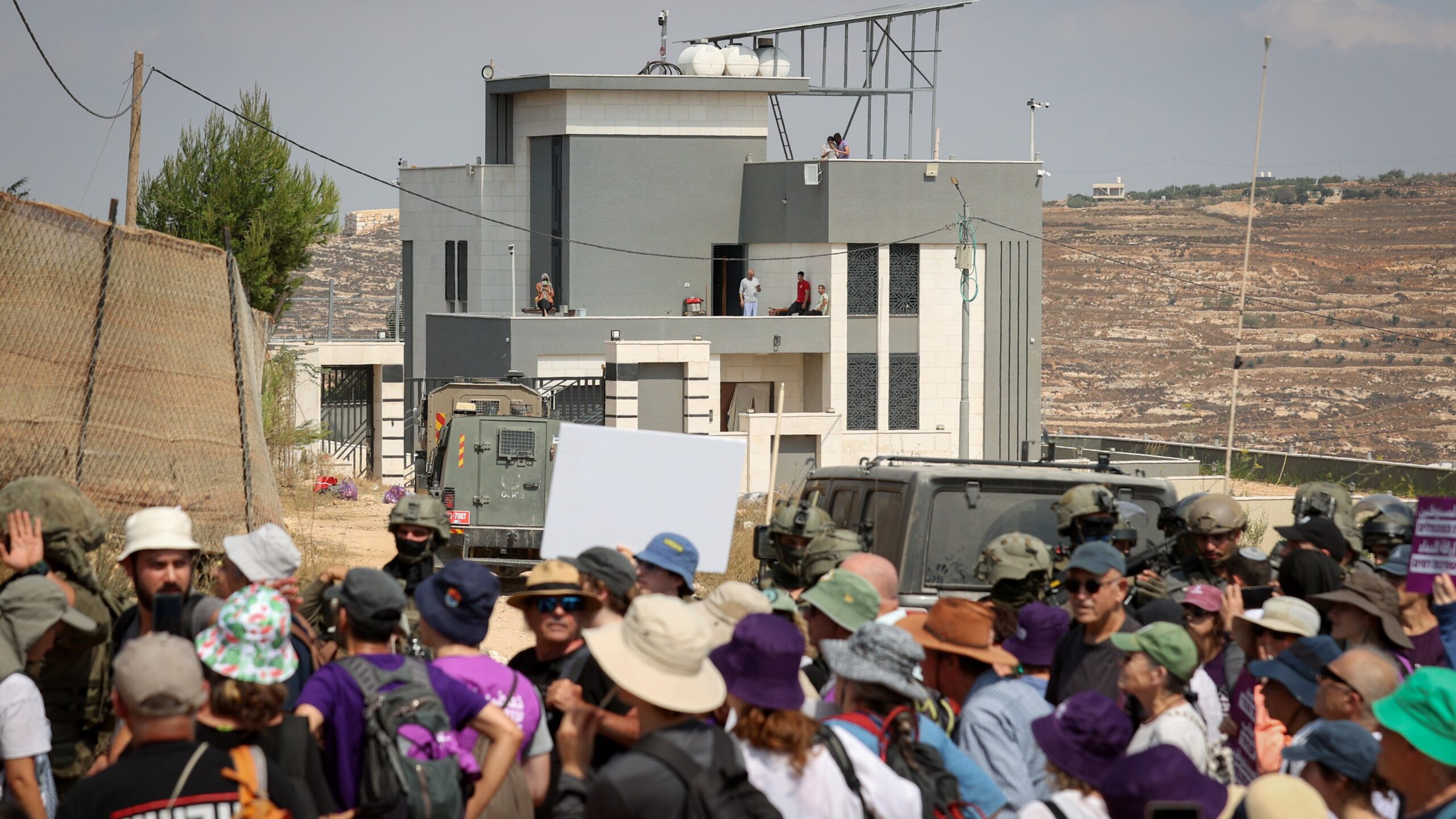 Israeli left-wing activists gather in Qusra in Samaria, while Palestinian residents and supporters stand on the roof of a house besieged by Israeli settlers, August 14, 2026. Photo: Flash90