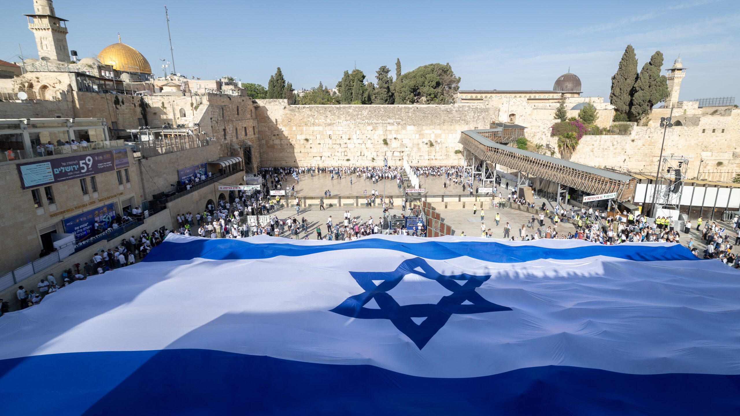 A shared identity unites: People hold a giant Israeli flag in front of the Western Wall in Jerusalem on the eve of Jerusalem Day, May 14, 2026. Photo: Yonatan Sindel/Flash90