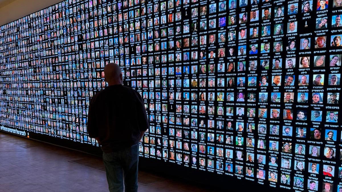 Aviel Schneider in front of the digital memorial wall at the National Library of Israel in Jerusalem. Thousands of faces commemorate the victims of October 7th and the fallen of the war. Photo: Aviel Schneider.