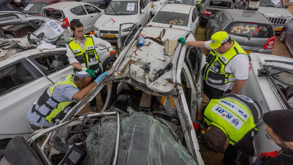 ZAKA personnel work at a field with destroyed cars from the Oct. 7 Hamas terrorist attacks, Dec. 12, 2023. Photo by Chaim Goldberg/Flash90.